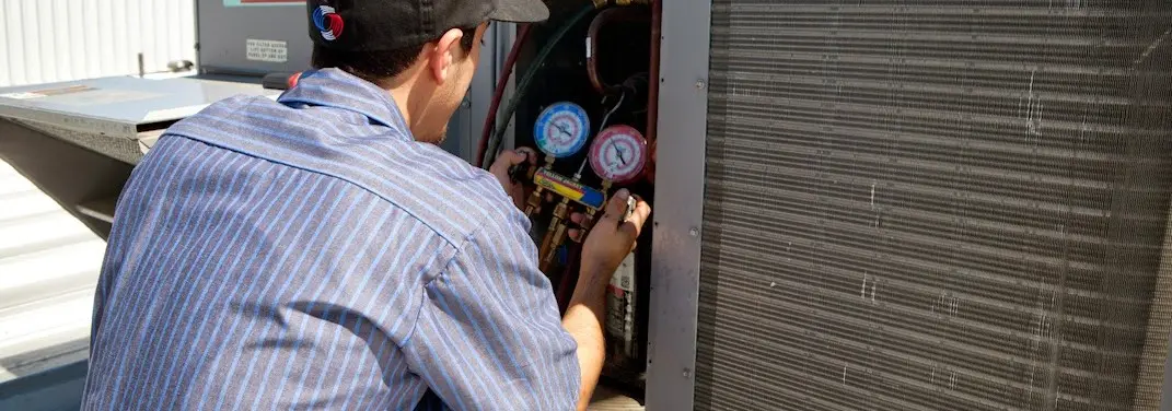 HVAC technician servicing a condenser unit in Youngstown